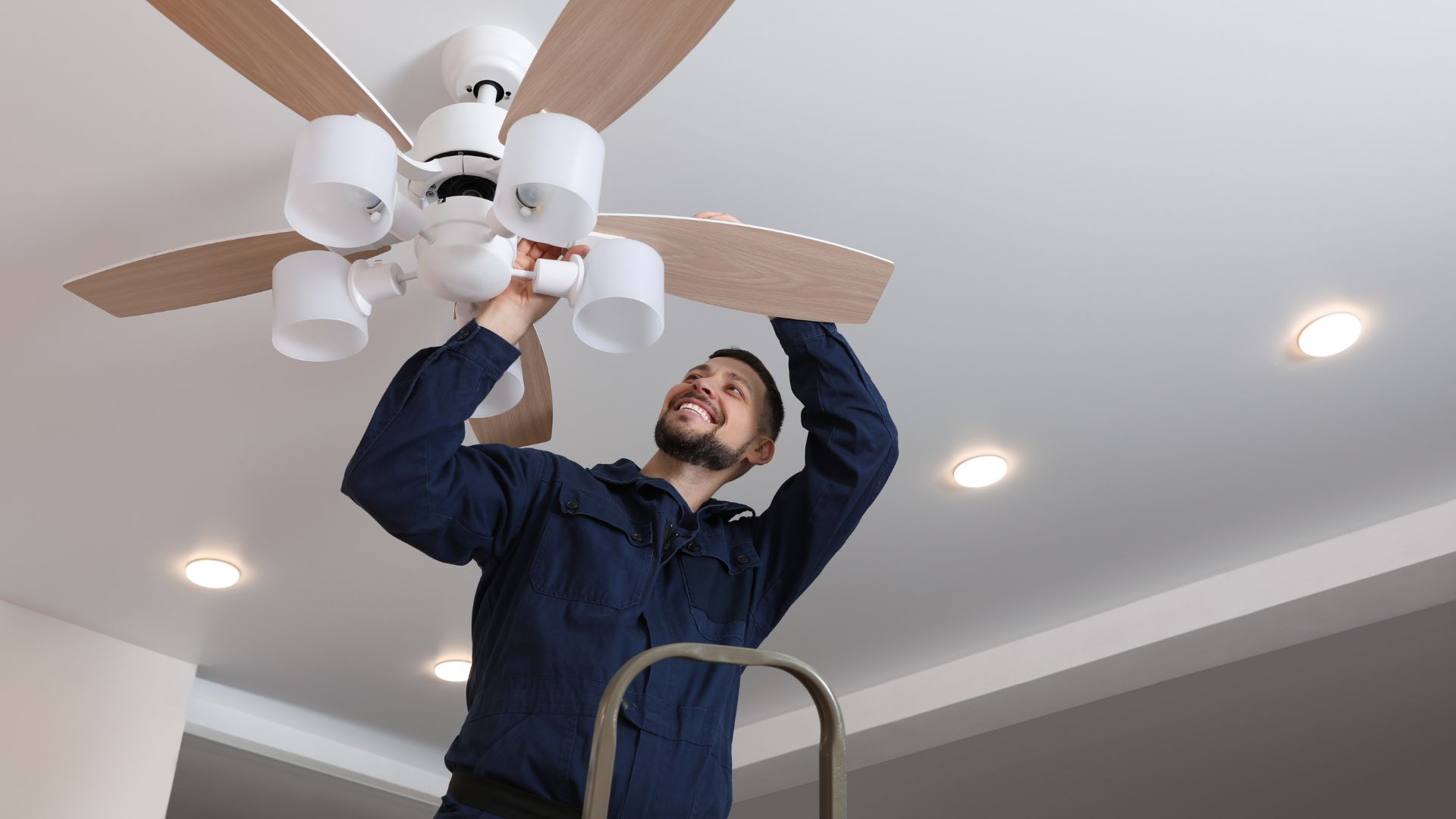 A man holding a ceiling fan in a room