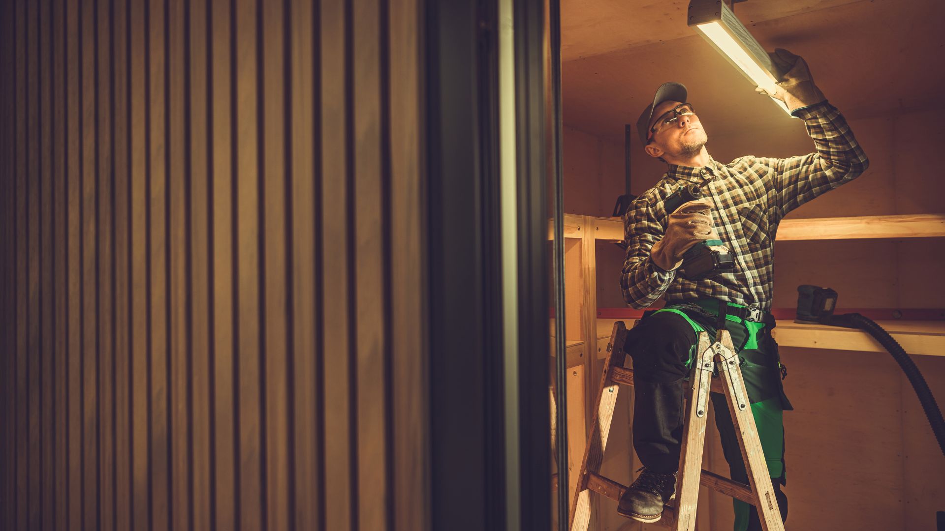 A man standing on a ladder working on a light fixture